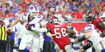 Buffalo Bills quarterback Josh Allen trying to make a play while being held by an opponent.